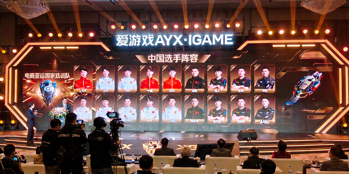 电竞亚运国家集训队名单公布仪式现场，大屏幕展示中国选手阵容，爱游戏AYX·IGAME品牌标识醒目呈现